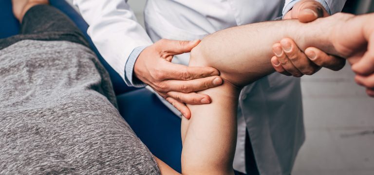 Ένας ιατρός εξετάζει τον αγκώνα ασθενούς στο ιατρείο.