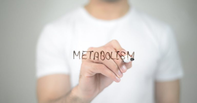 Άνδρας με λευκό μπλουζάκι γράφει τη λέξη METABOLISM σε διάφανη επιφάνεια, εικόνα για τη μεταβολική υγεία